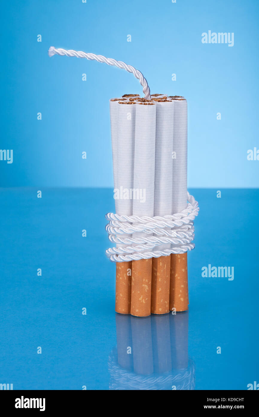 Cigarettes Tied With Rope And Wick Over Blue Background Stock Photo