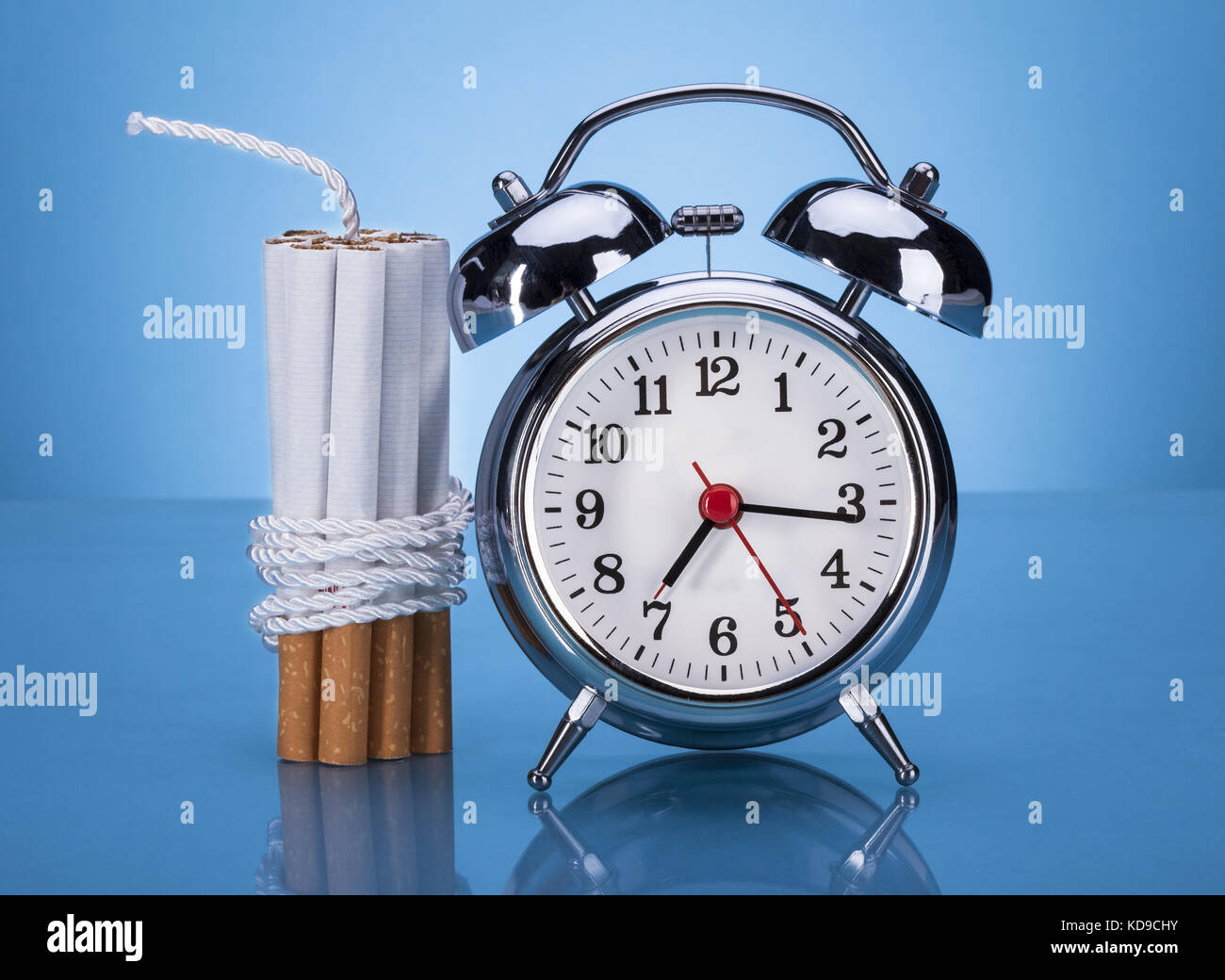 Cigarettes Tied With Rope And Alarm Clock Over Blue Background Stock Photo