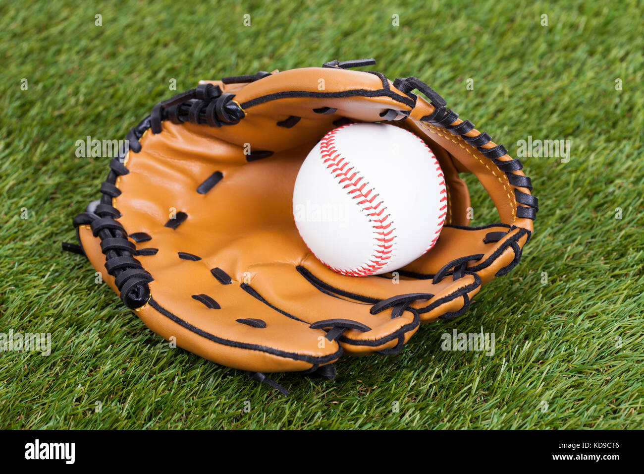 Leather Glove With Baseball Ball On Green Pitch Stock Photo