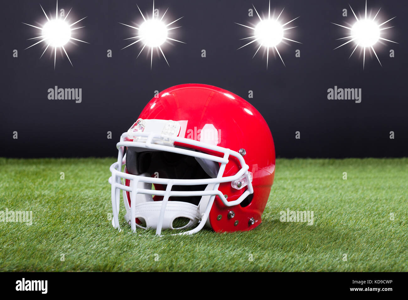 Red Sports Helmet Lying On Green Grass Field Stock Photo