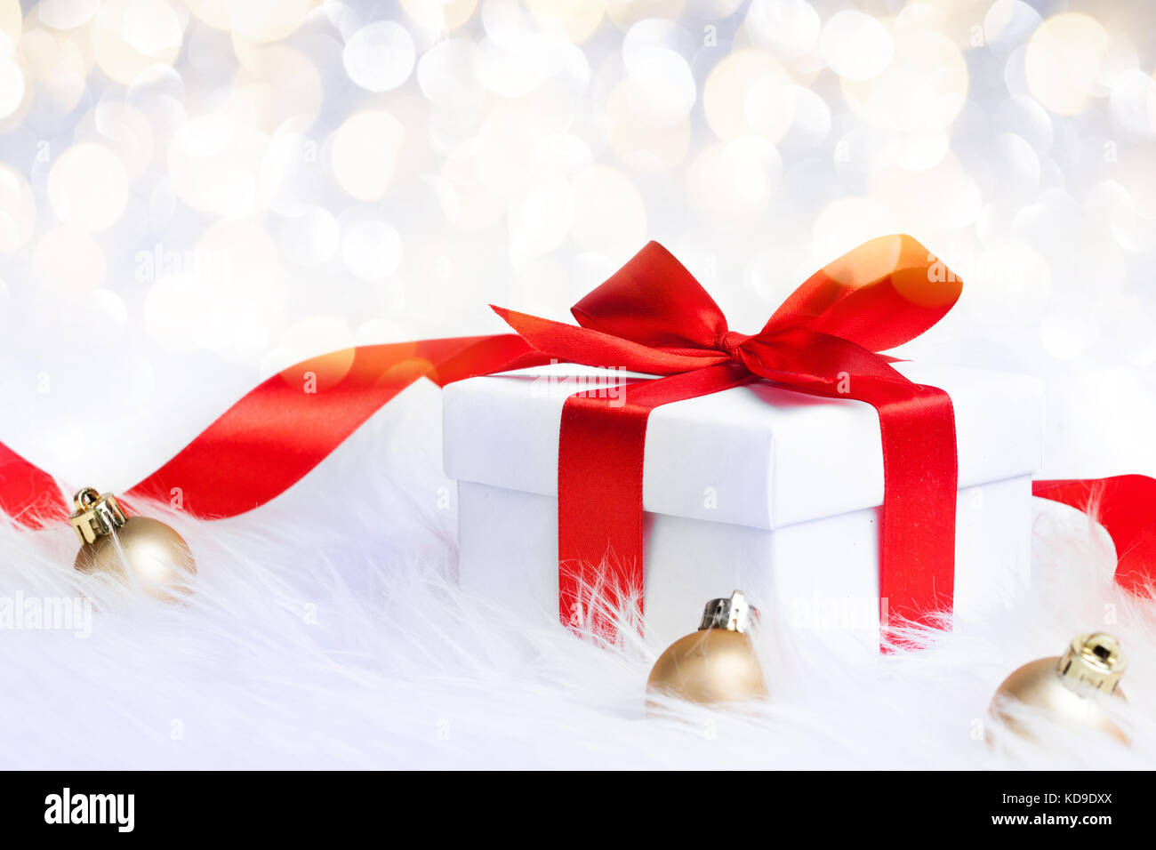 Gift box with red ribbon bow and christmas ball on glitter background ...