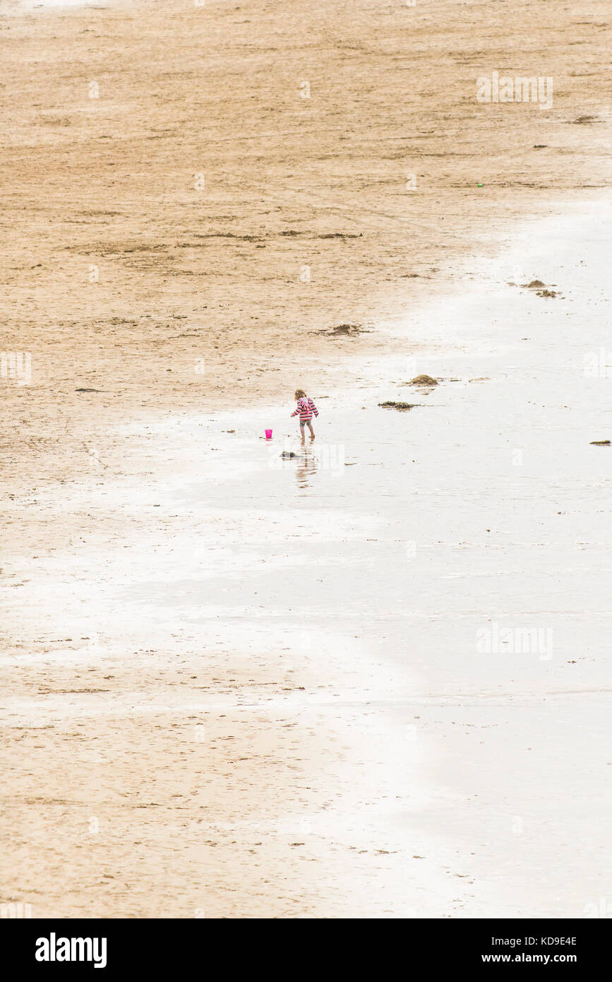 Fistral Beach in Newquay, Cornwall - a young child playing on her own on a beach in Cornwall. Stock Photo