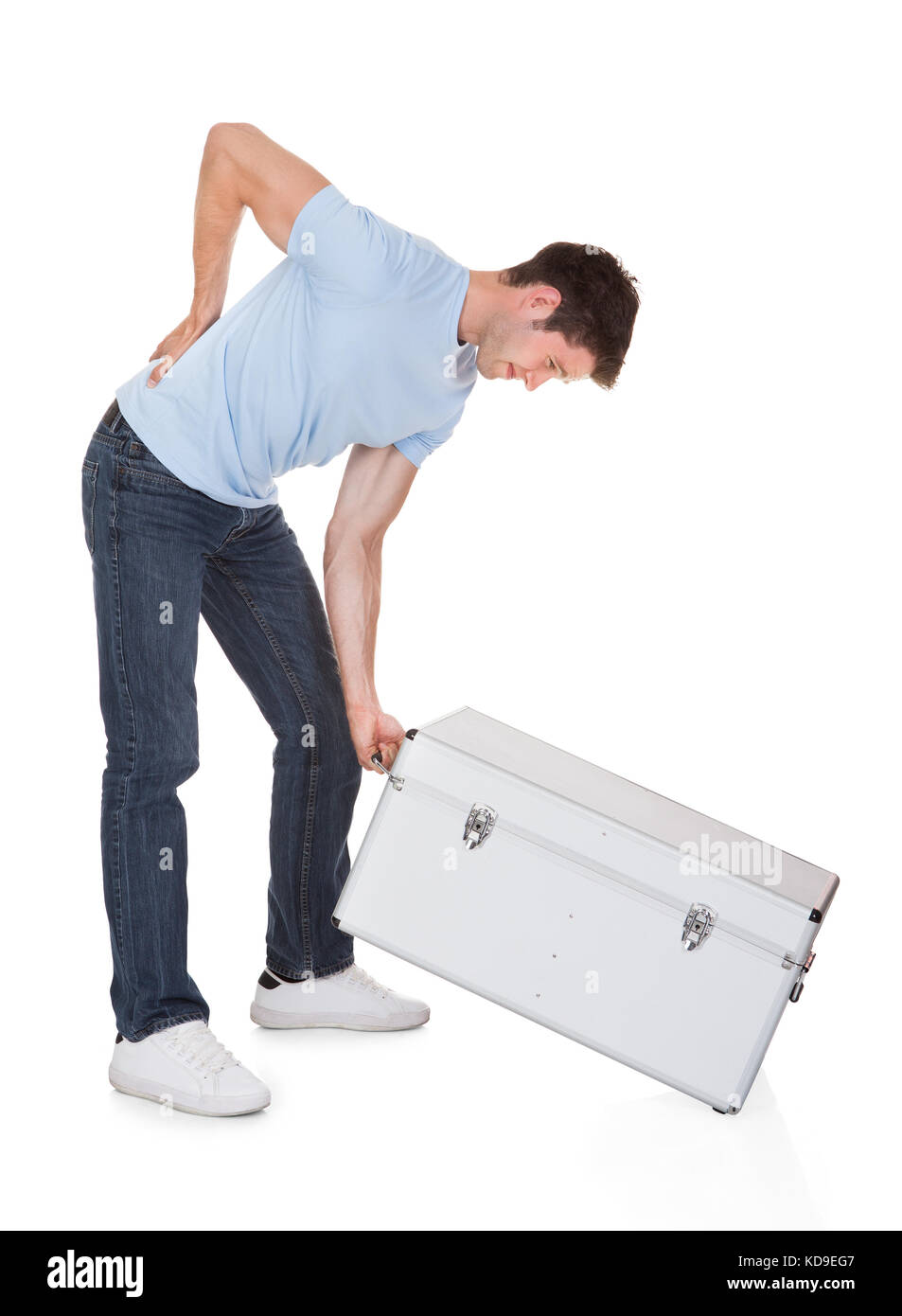 Young Man With Back Pain Lifting Metal Box Isolated On White Background Stock Photo