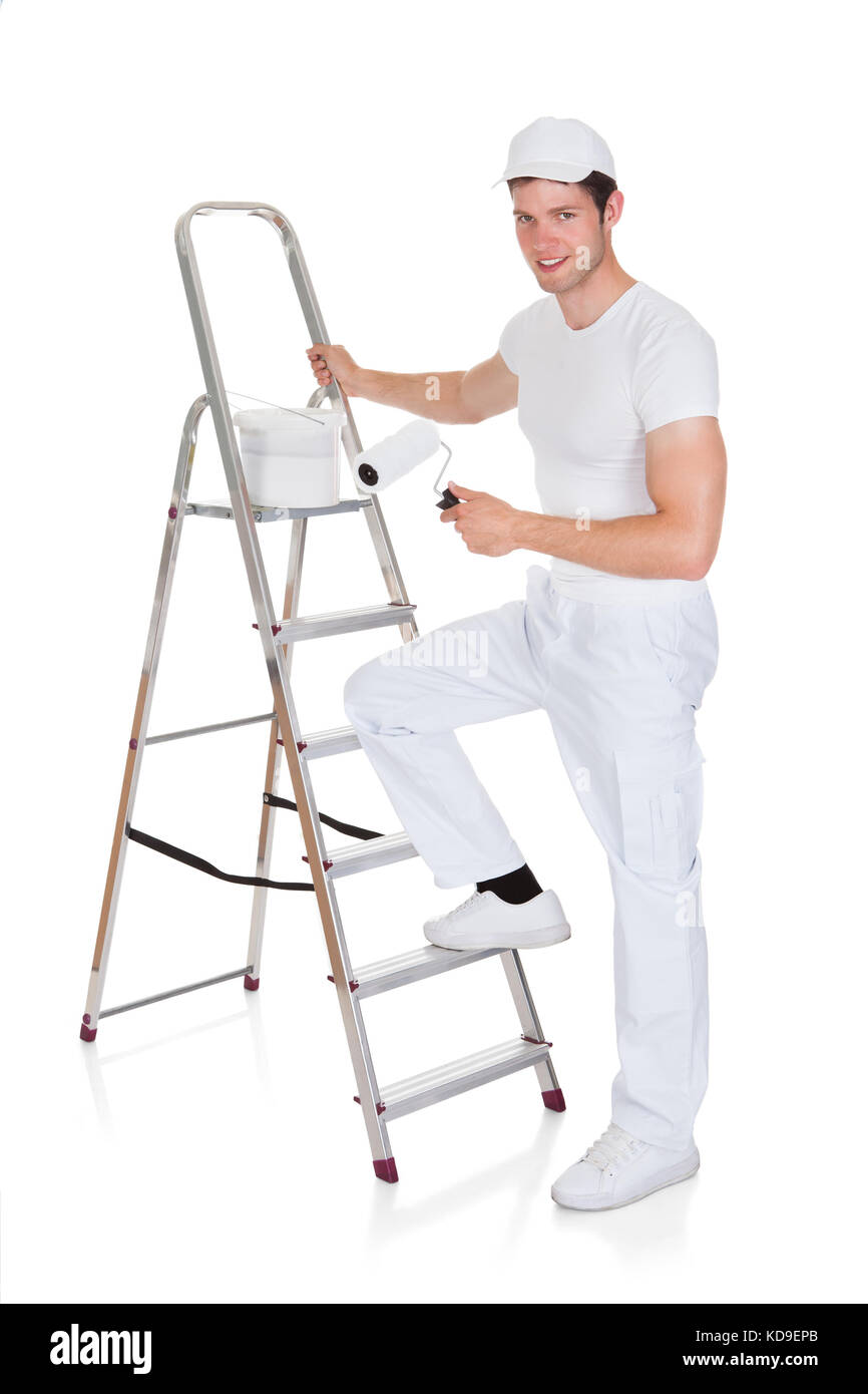 Happy Painter With Paint Bucket And Roller Standing On Ladder Stock