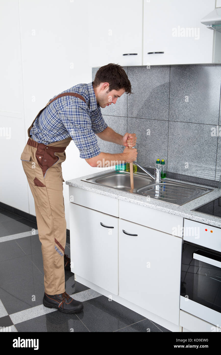Young Handsome Man Using Plunger In Kitchen Sink Stock Photo Alamy