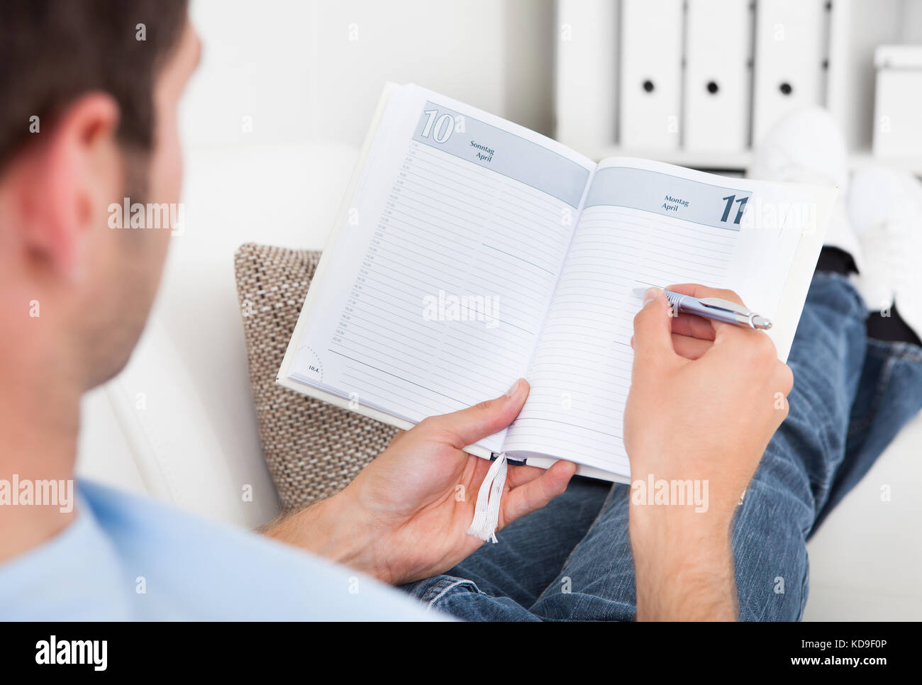 Close-up Of A Young Man Sitting On Couch Writing In Diary Stock Photo ...