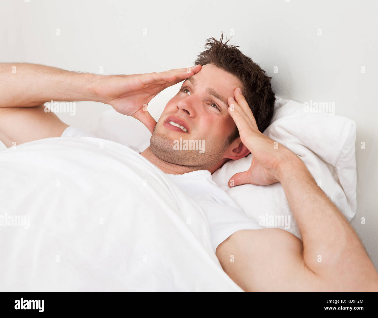 Young Man Suffering From Headache Lying On Bed Stock Photo Alamy