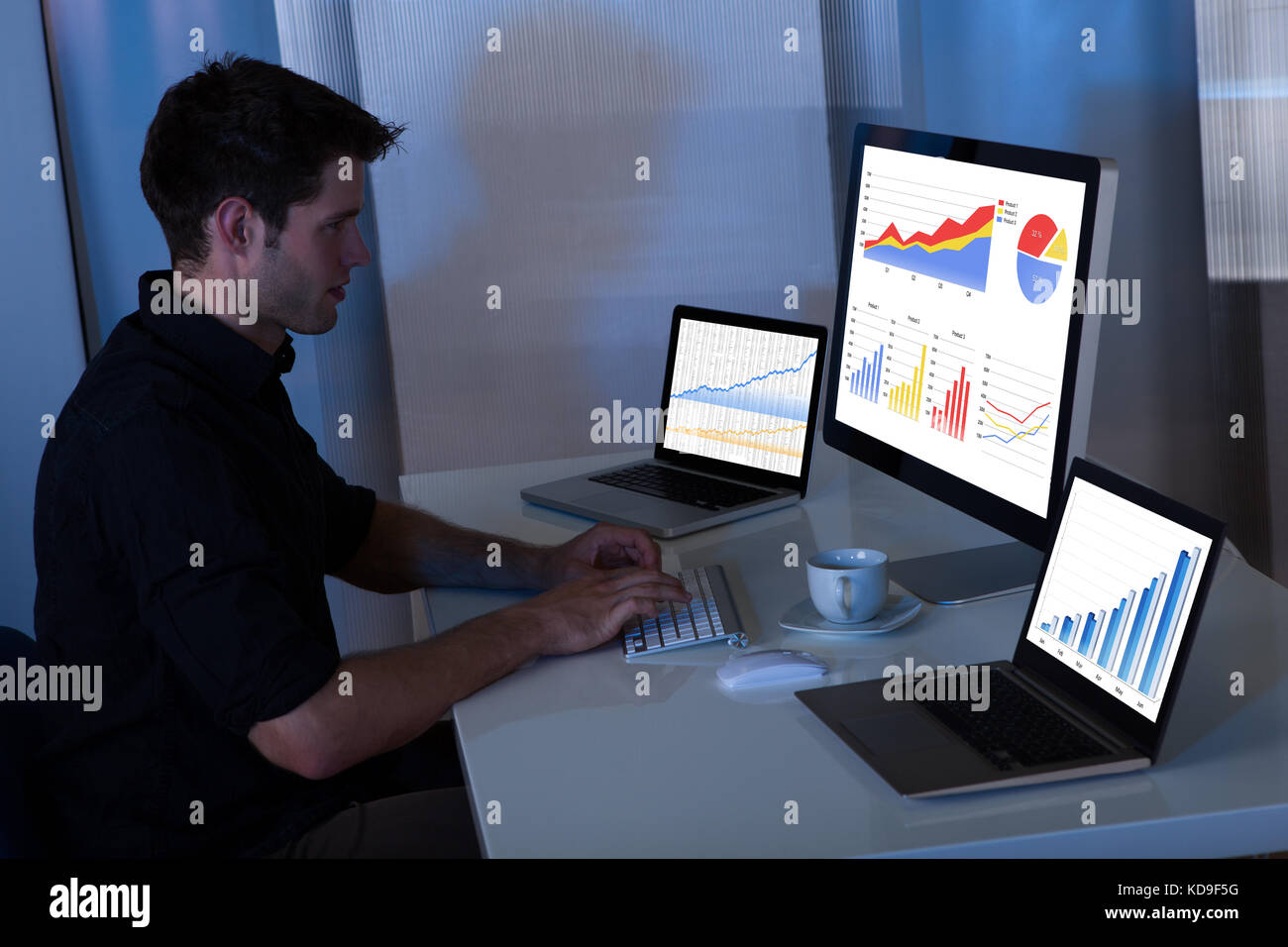 Young man working at computer in the office at night Stock Photo