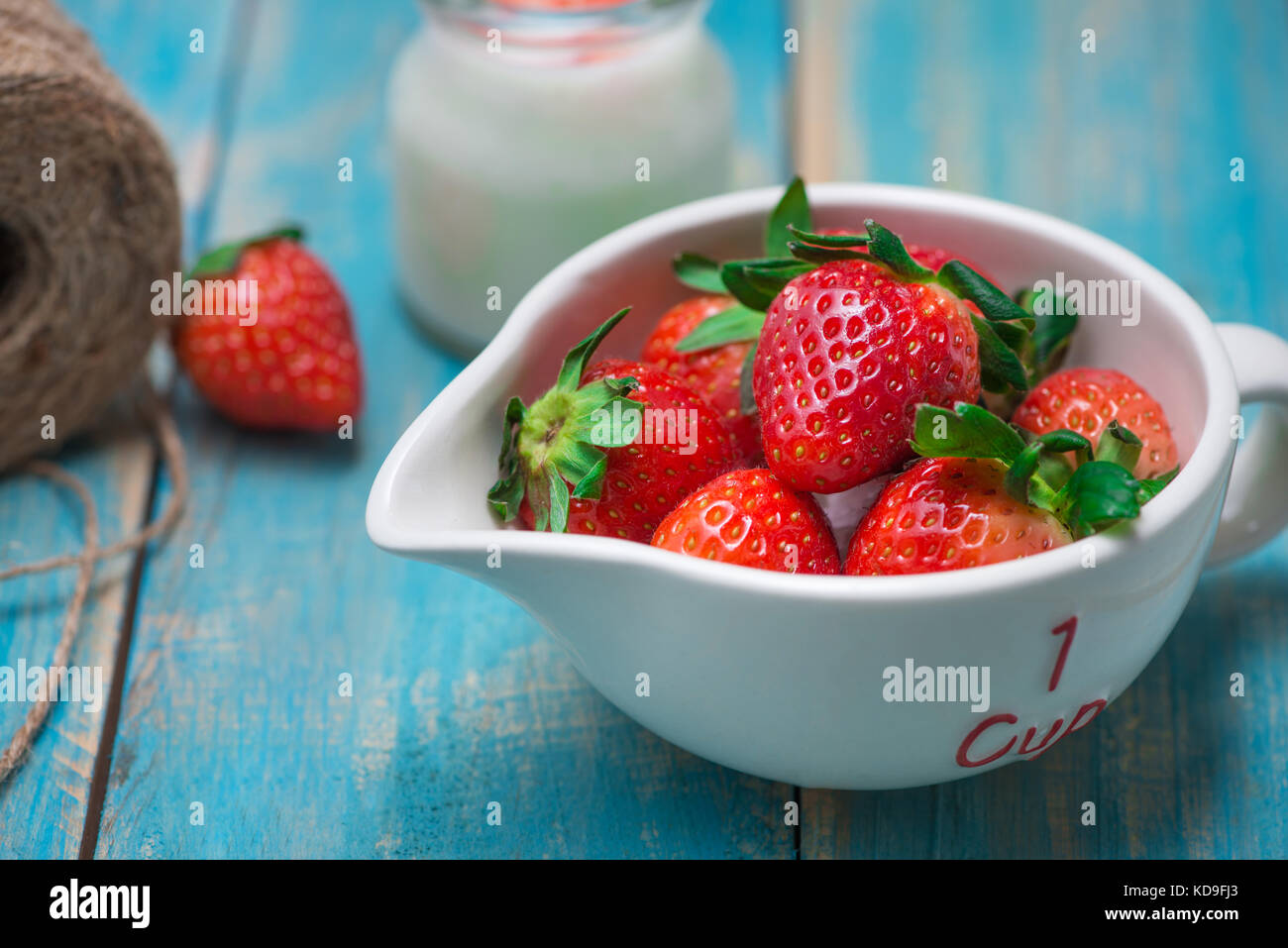 Bowl with fresh strawberry on blue wooden table Stock Photo - Alamy