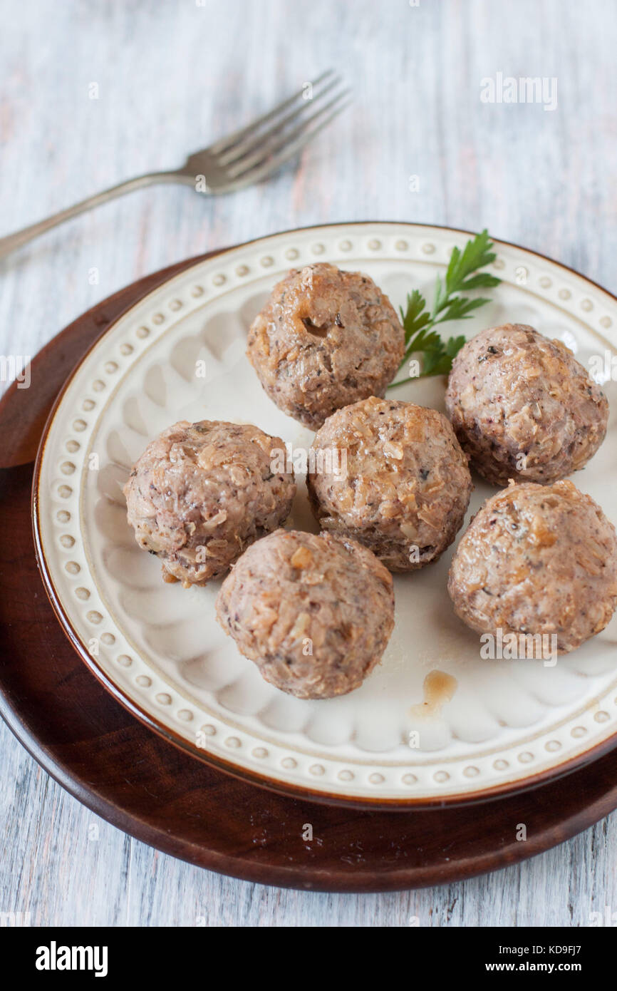 Six pork meatballs without sauce on beige plate over wood plate on light blue background with a fork Stock Photo