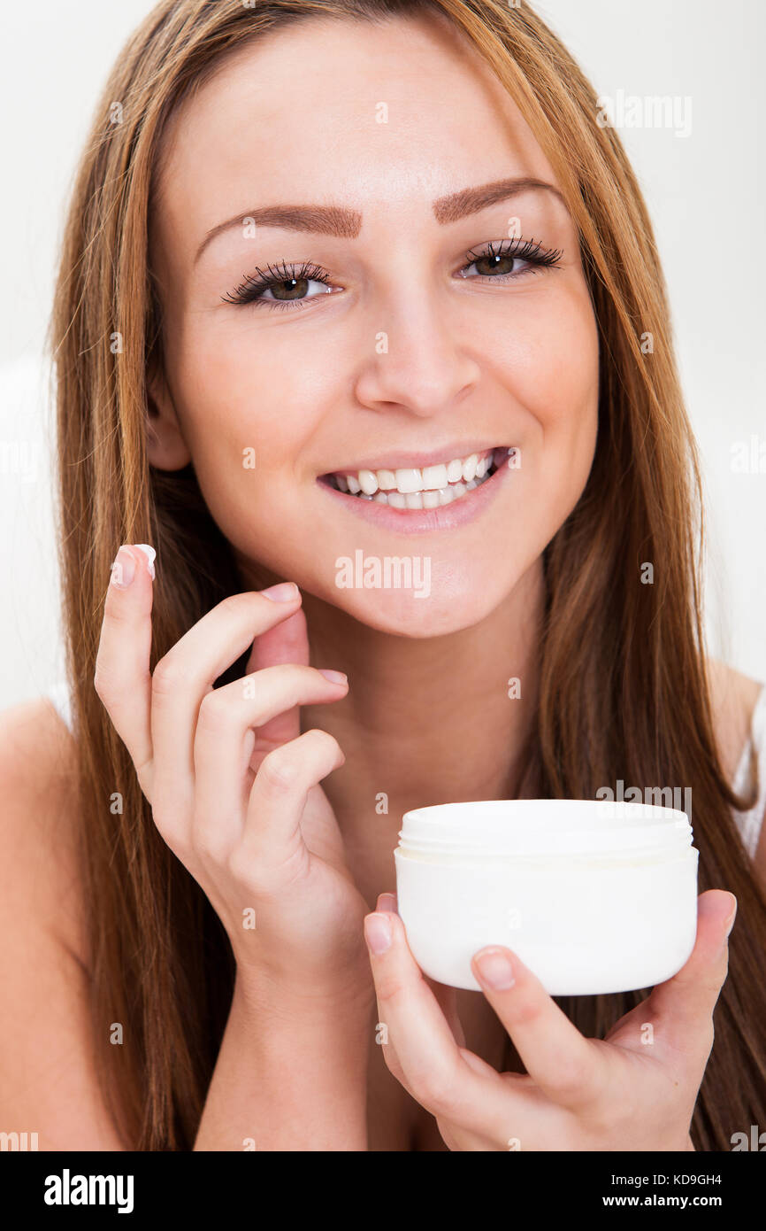 Attractive Young Woman Applying Moisturizer To Her Cheek Stock Photo