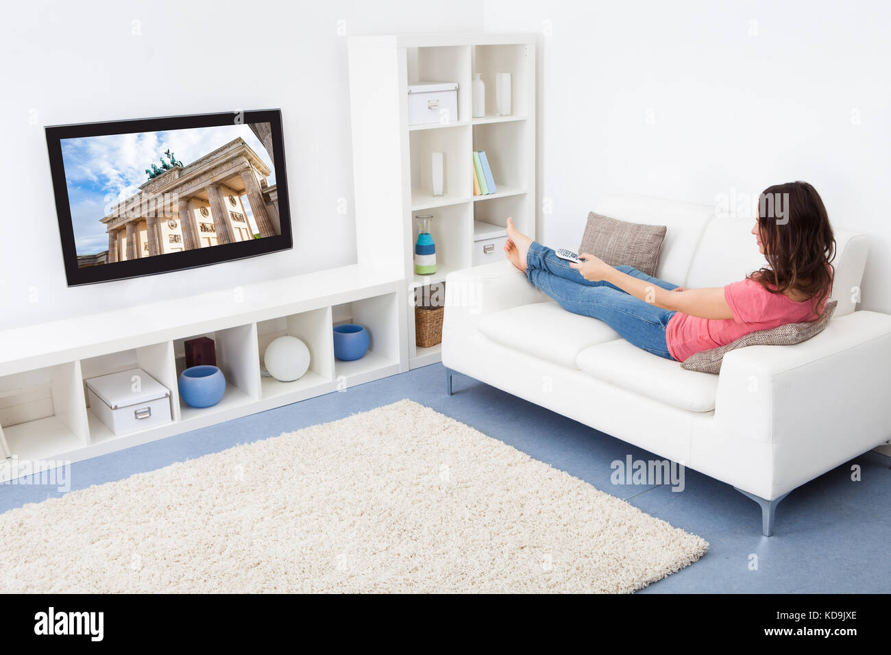 Portrait Of Smiling Woman Sitting On Couch Watching Television Stock Photo