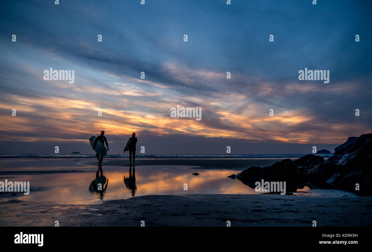 surfers and sunset reflected in water Stock Photo