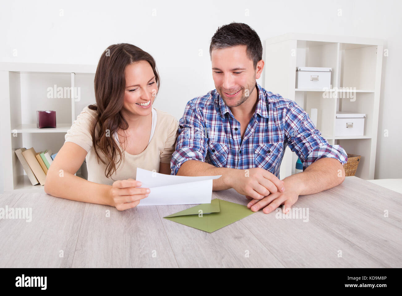 Portrait Of A Happy Young Couple At Home Reading Paper Stock Photo - Alamy
