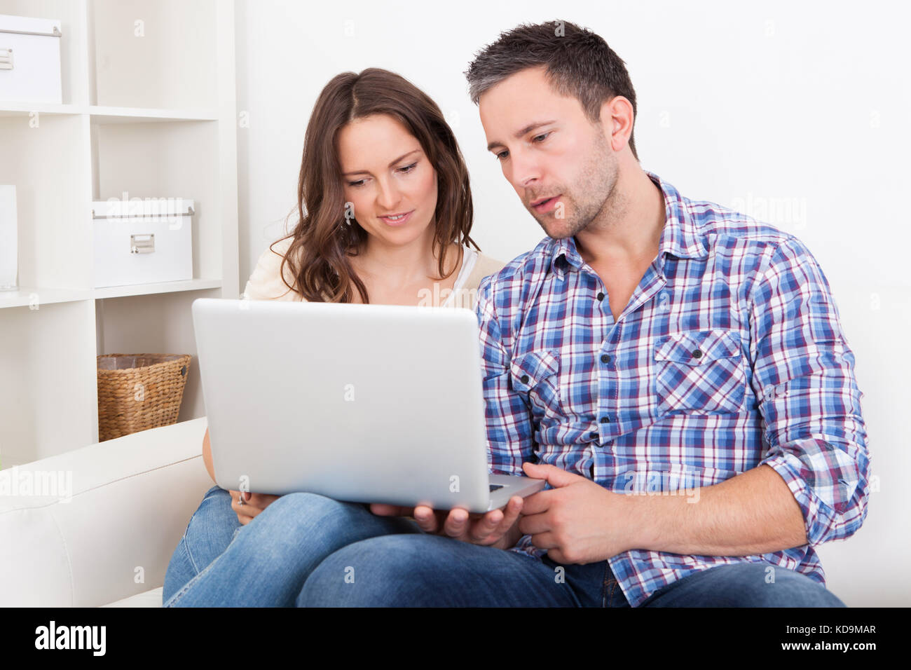 Portrait Of A Happy Young Couple Sitting On Couch Using Laptop Stock ...