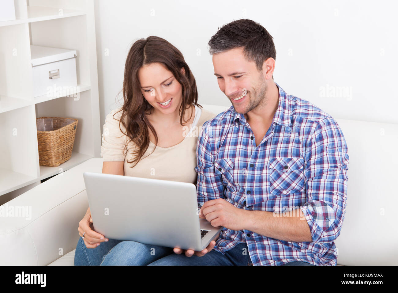 Portrait Of A Happy Young Couple Sitting On Couch Using Laptop Stock ...