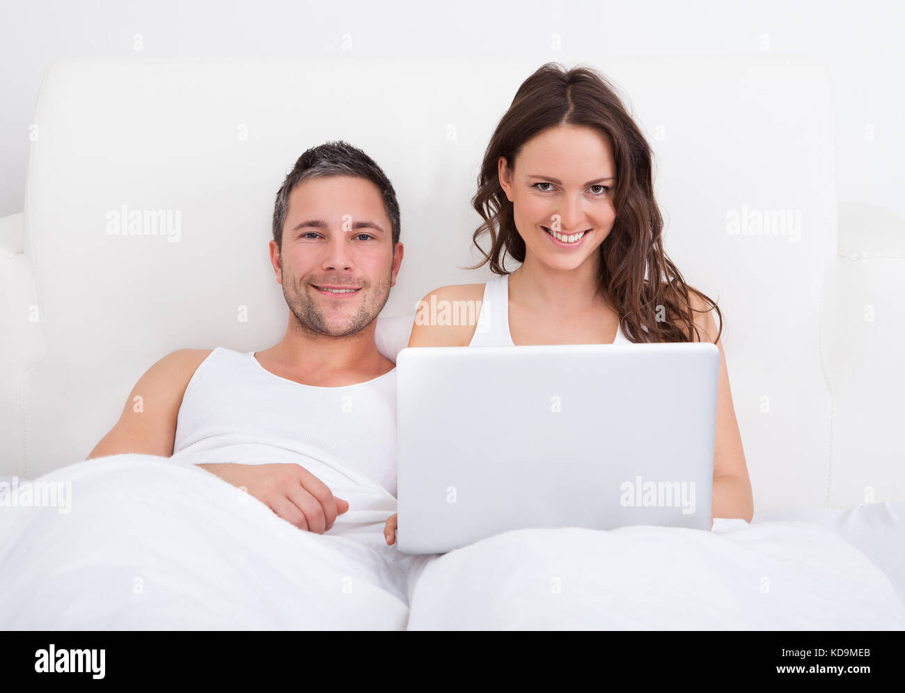 Portrait Of Smiling Couple Lying On Bed Using Laptop Stock Photo - Alamy