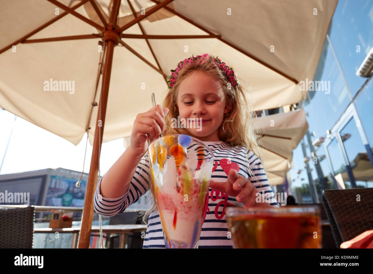 Little girl eating ice cream in outdoor cafe. Stock Photo