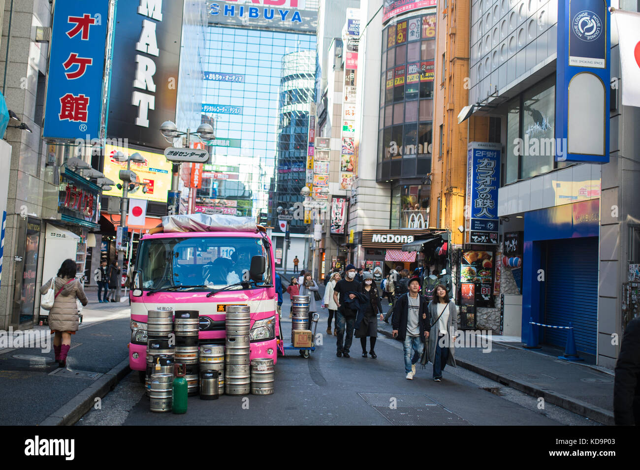 TOKYO - JAPAN - JANUARY 4, 2017. A pink truck with barrels is parked in the streets of Shinjuku while people walk around. Shinjuku is a special ward i Stock Photo