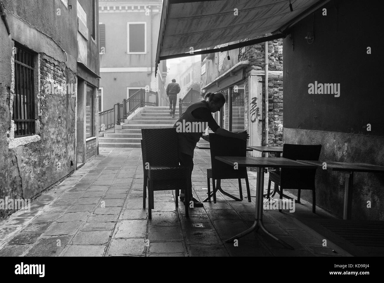 Venice, Italy. 11th October, 2017. (PICTURES HAS BEEN TAKEN IN BLACK AND WHITE)  A woman sets up a restaurant in the morning with fog in Venice, Italy. In this period in Venice starts the first foggy mornings. © Simone Padovani / Awakening / Alamy Live News Stock Photo