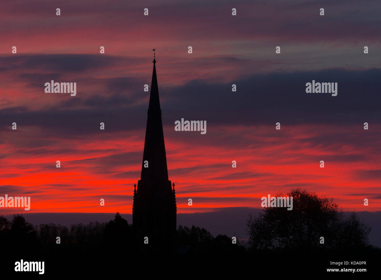 Sherbourne, Warwickshire, UK. 12th Oct, 2017. UK Weather. A spectacular dawn sky forms a backdrop to the spire of All Saints Church at Sherbourne, a village in Warwickshire. The Victorian Gothic church was designed by the eminent architect Sir George Gilbert Scott. Credit: Colin Underhill/Alamy Live News Stock Photo