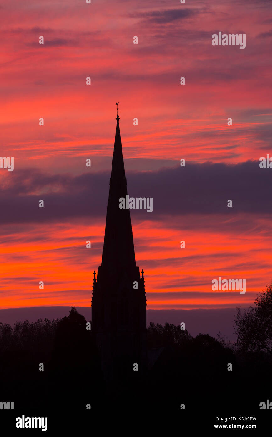 Sherbourne, Warwickshire, UK. 12th Oct, 2017. UK Weather. A spectacular dawn sky forms a backdrop to the spire of All Saints Church at Sherbourne, a village in Warwickshire. The Victorian Gothic church was designed by the eminent architect Sir George Gilbert Scott. Credit: Colin Underhill/Alamy Live News Stock Photo