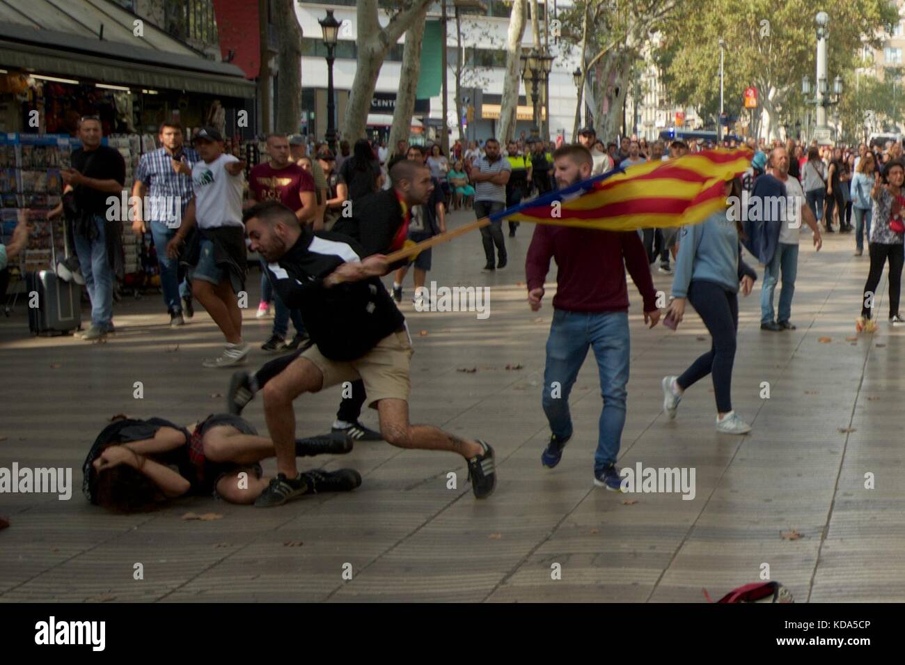 Barcelona, Spain. 12th Oct, 2017.  Scuffles break out on the Rambla on Spain's National holiday. An opponent of Catalan independence knocks an independence supporter to the floor and strikes him with his Estrelada flag. Credit: Luke Peters/Alamy Live News Stock Photo