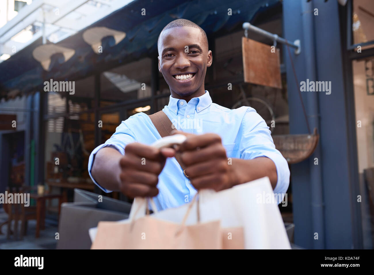 Stylish young man standing outside holding up shopping bags Stock Photo