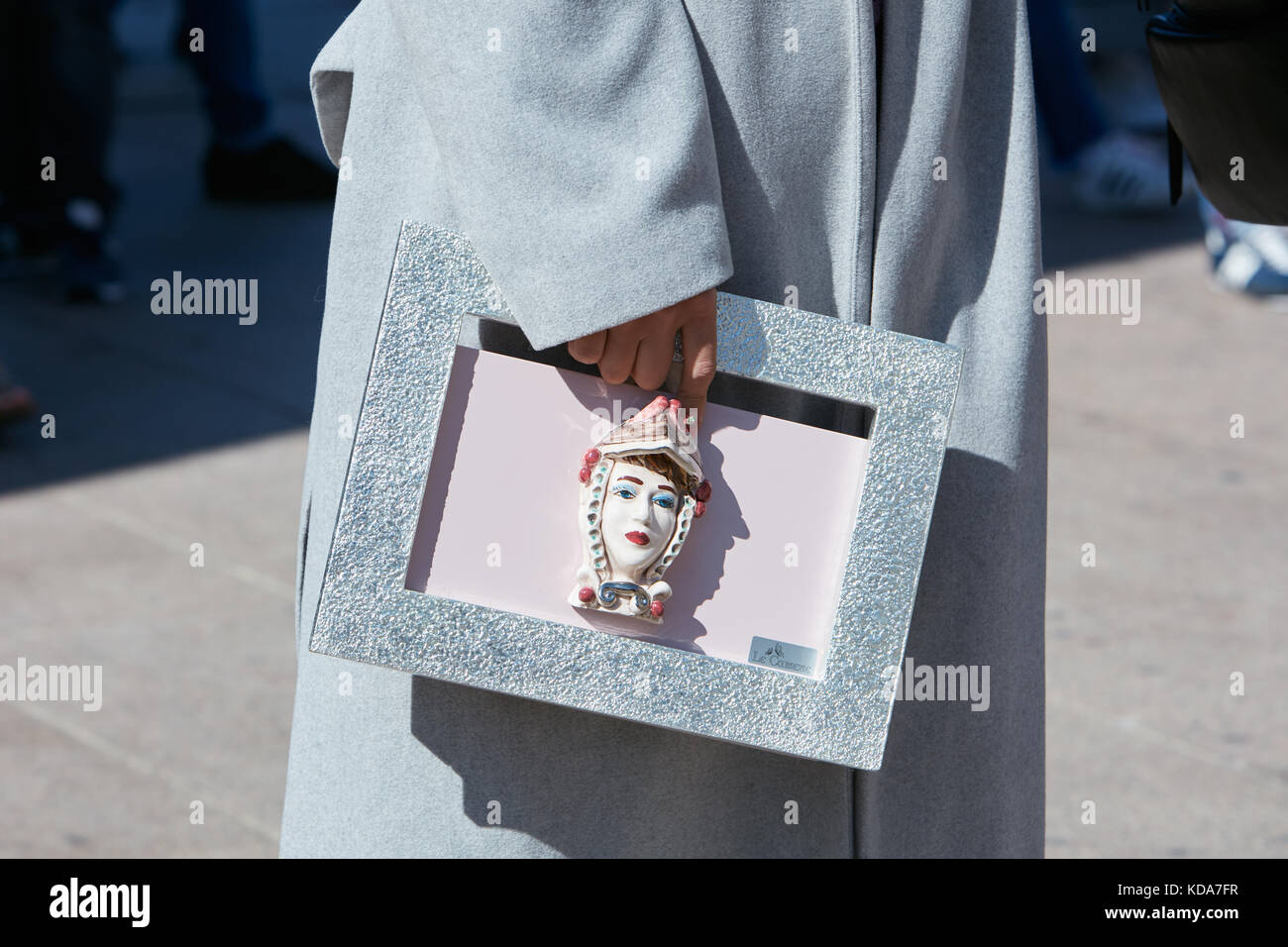 MILAN - SEPTEMBER 20: Woman with silver bag with porcelain head and gray coat before Cristiano Burani fashion show, Milan Fashion Week street style on Stock Photo