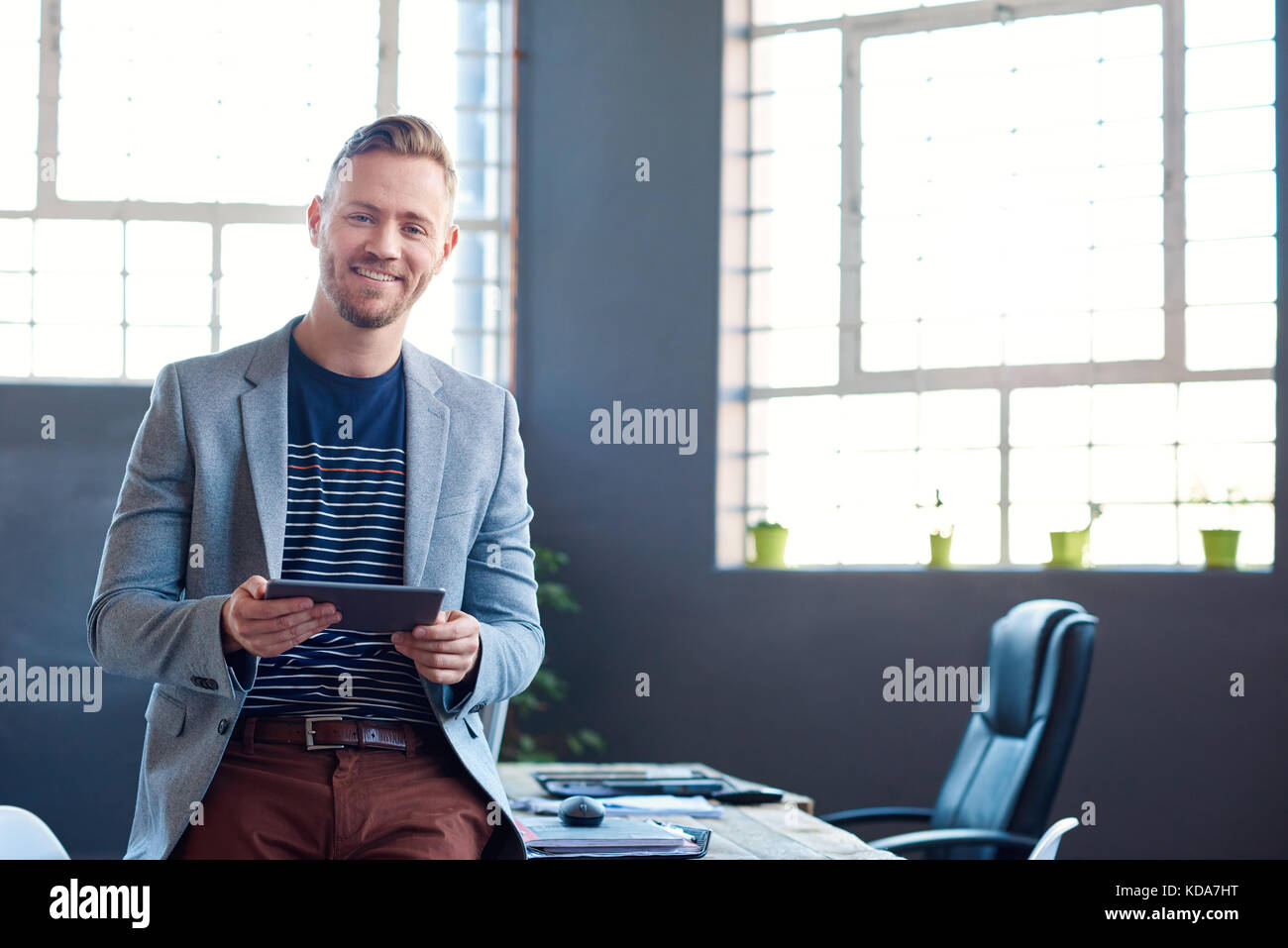 Smiling young businessman using a tablet in an office Stock Photo - Alamy