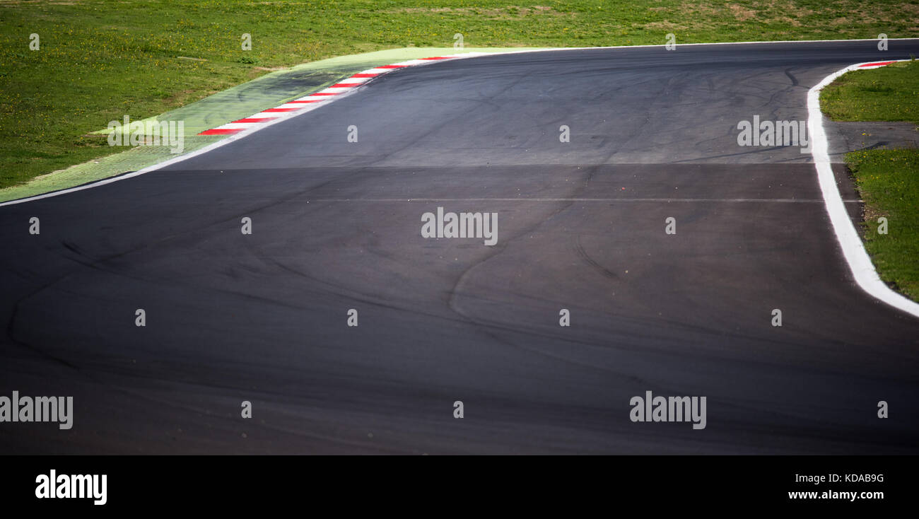 Empty motorsport circuit asphalt track, round and curb, green grass outside Stock Photo