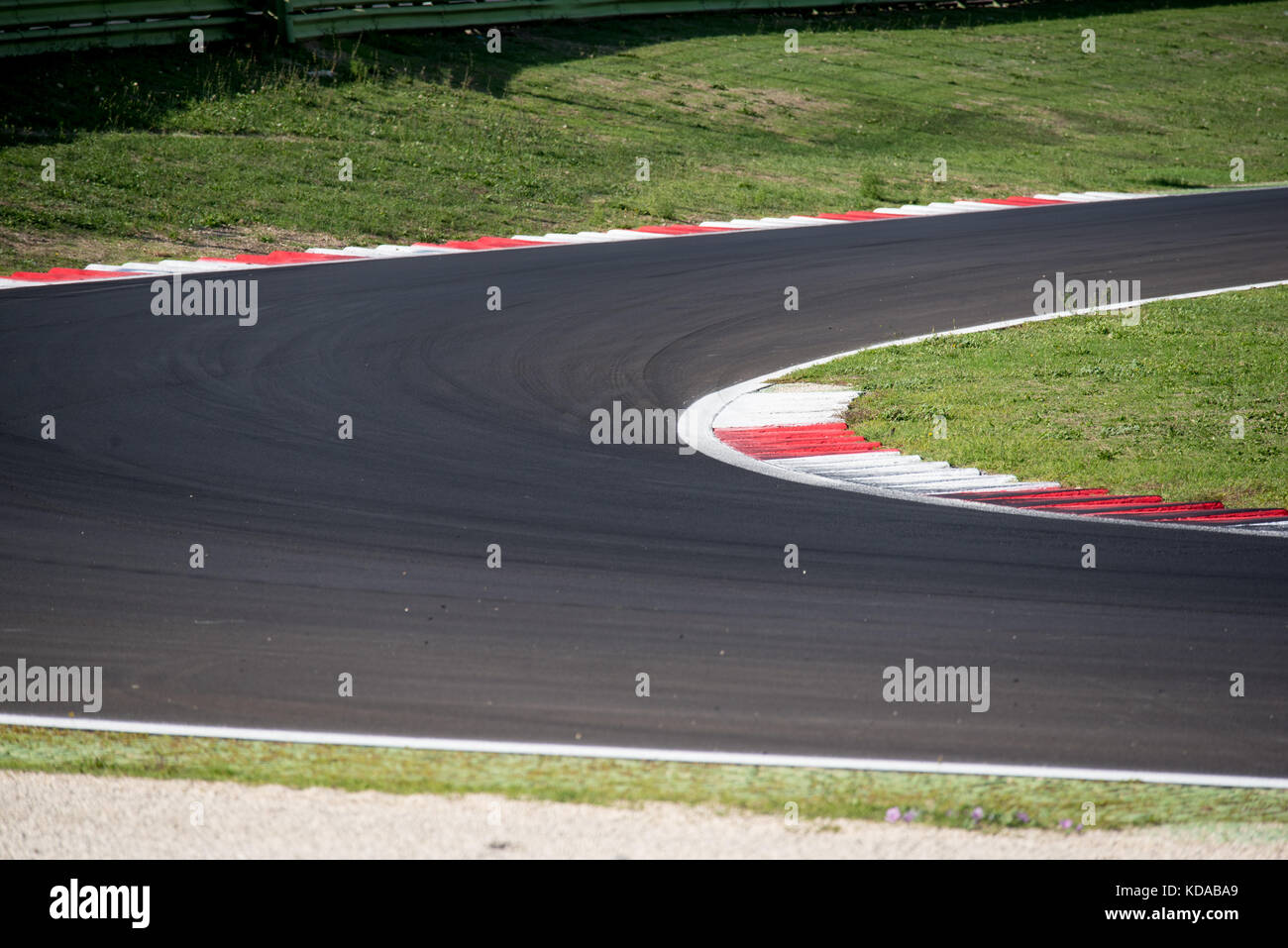 Empty motorsport circuit asphalt track, round and curb, green grass outside, concept of racing and competition Stock Photo