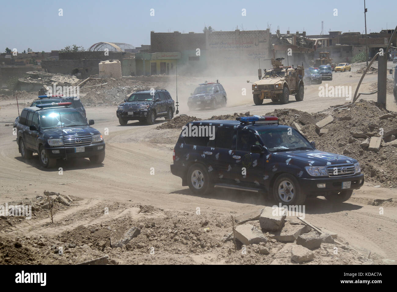 Iraqi Federal Police officers escort U.S. soldiers through an Iraqi neighborhood recently liberated from ISIS extremists June 7, 2017 in Mosul, Iraq. Stock Photo