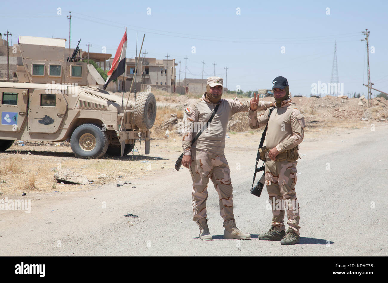 Iraqi Army soldiers greet a convoy of U.S. soldiers May 25, 2017 in Mosul, Iraq. There has been a combined effort between U.S. and Iraqi forces in the area to defeat ISIS extremists. Stock Photo