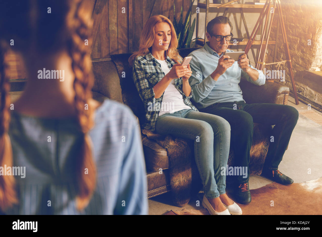 Married couple with phones ignoring their child Stock Photo