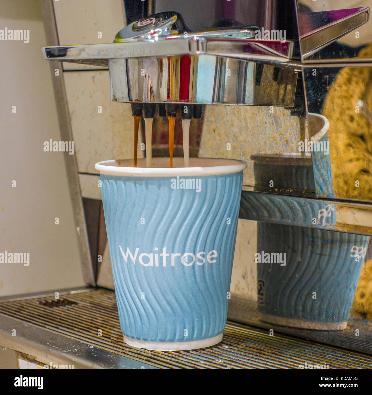 A paper cup filling with coffee which is flowing from a machine at the Peterborough branch of Waitrose supermarket, Cambridgeshire, England, UK. Stock Photo