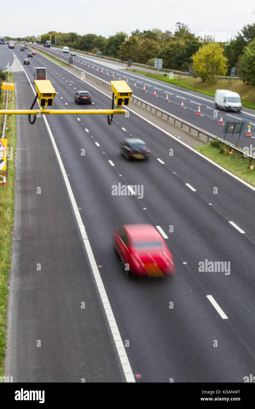 Bright yellow speed cameras in an average speed check area with moving traffic flowing through a roadworks area on a British motorway or carriageway. Stock Photo