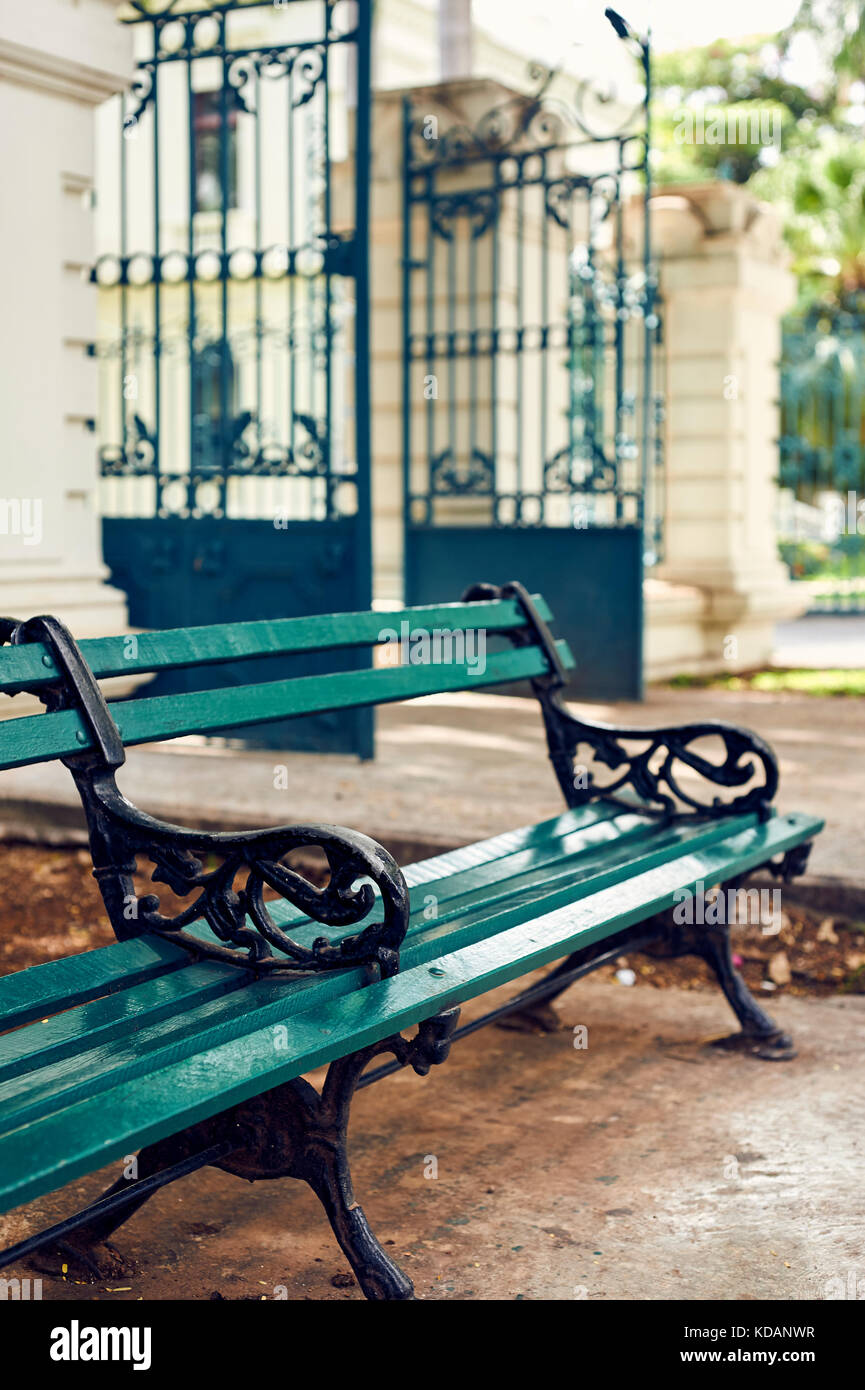 Green bench and gate on the sidewalk of Paseo de Montejo avenue in Merida, Yucatan, Mexico Stock Photo