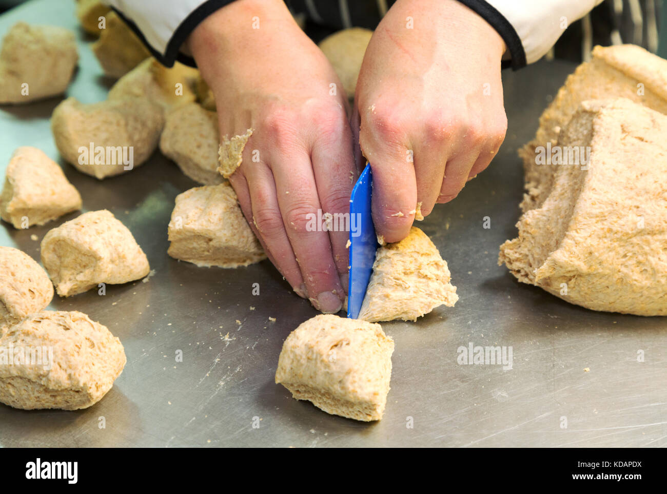 Making bread a person cutting up dough to make small loaves of bread