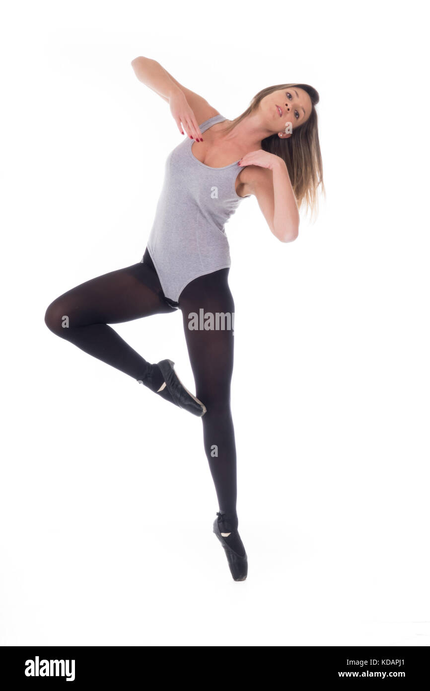 young beautiful woman dancer with long black hair wearing gray vest and tights jumping on a light white studio background Stock Photo