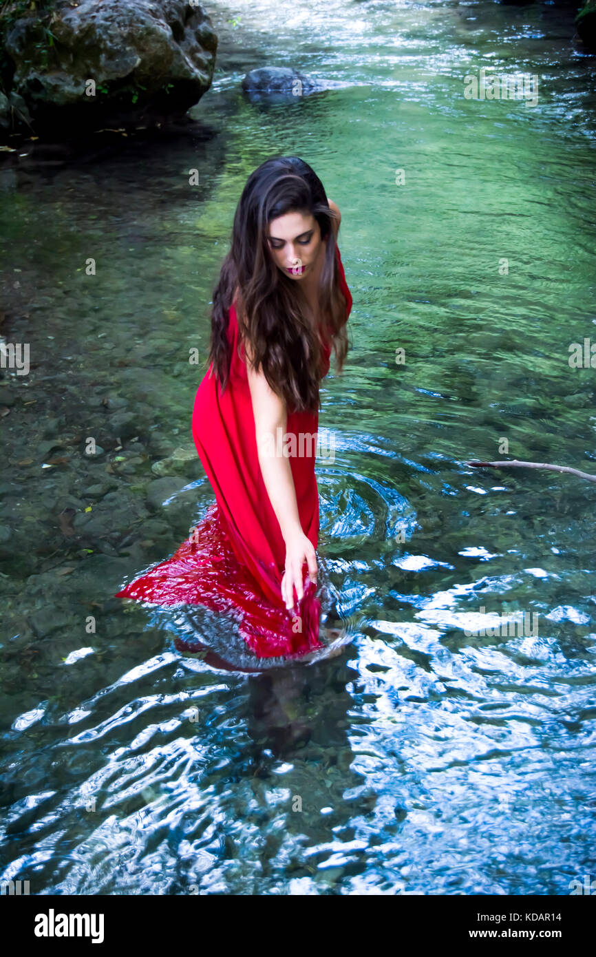 Beautiful woman on the bank of a mountain river with an evening dress ...