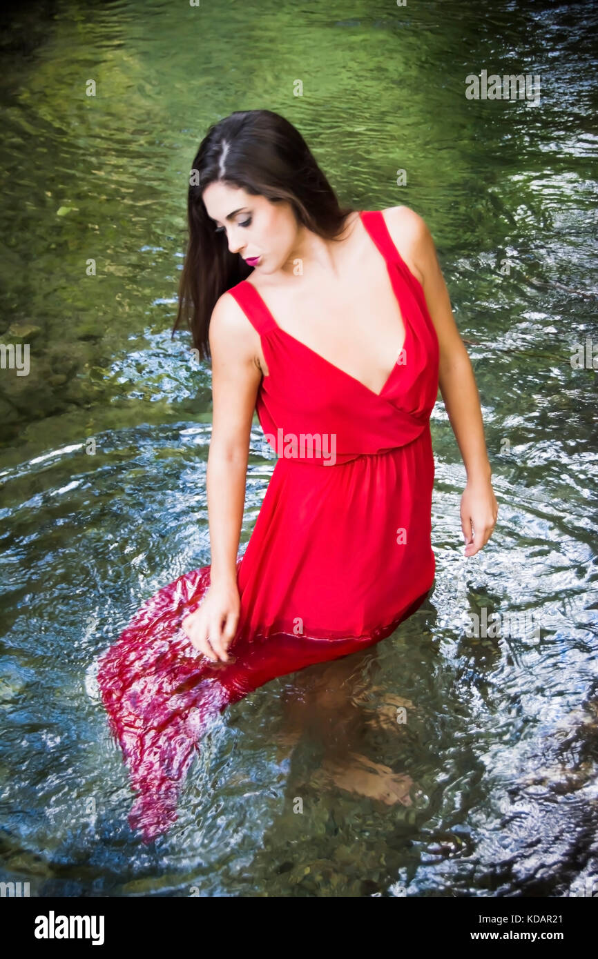 Beautiful woman on the bank of a mountain river with an evening dress ...