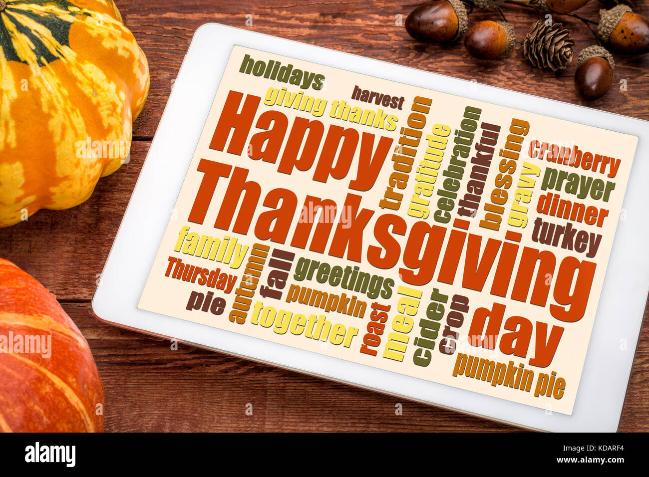 Happy Thanksgiving word cloud on a digital tablet with pumpkin and acorn decoration Stock Photo
