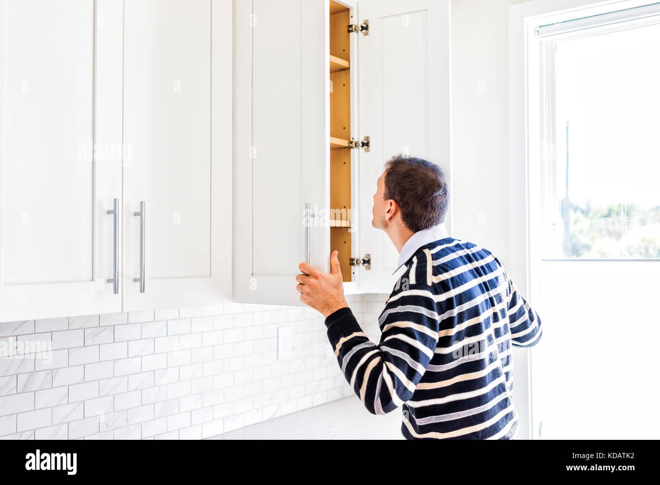 Young man checking looking inside empty kitchen modern by