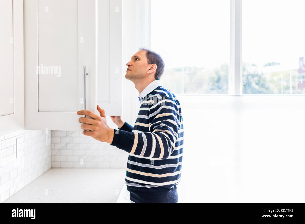 Young man checking looking inside empty kitchen modern by