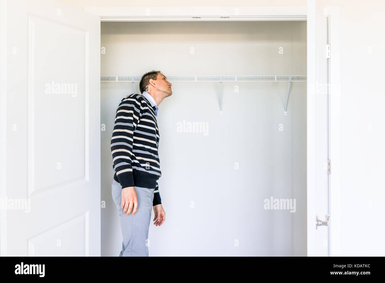 Young man checking looking inside small closet in new room after or before moving in, during open house Stock Photo