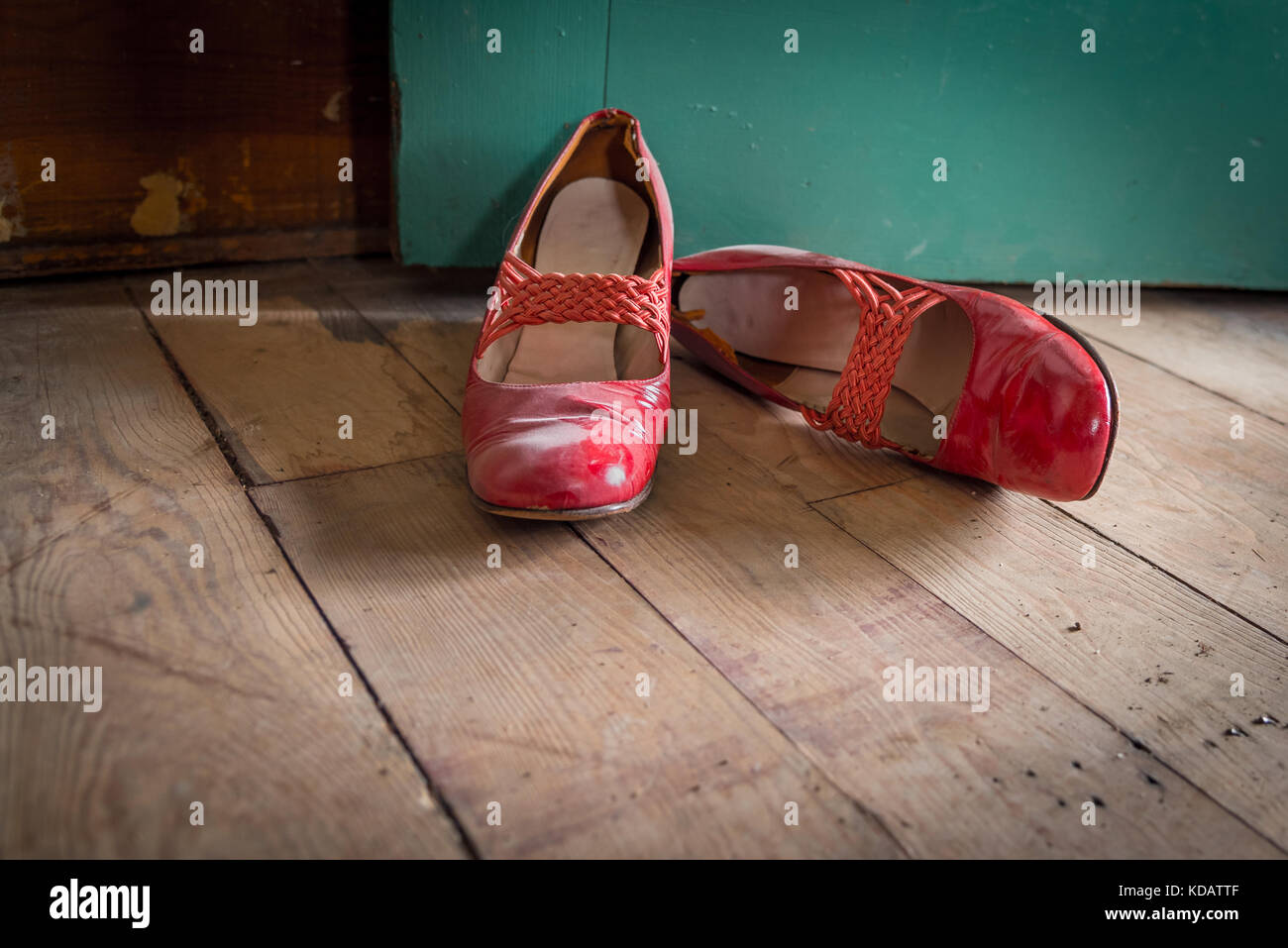 Worn red women's dress shoes on wooden floor Stock Photo