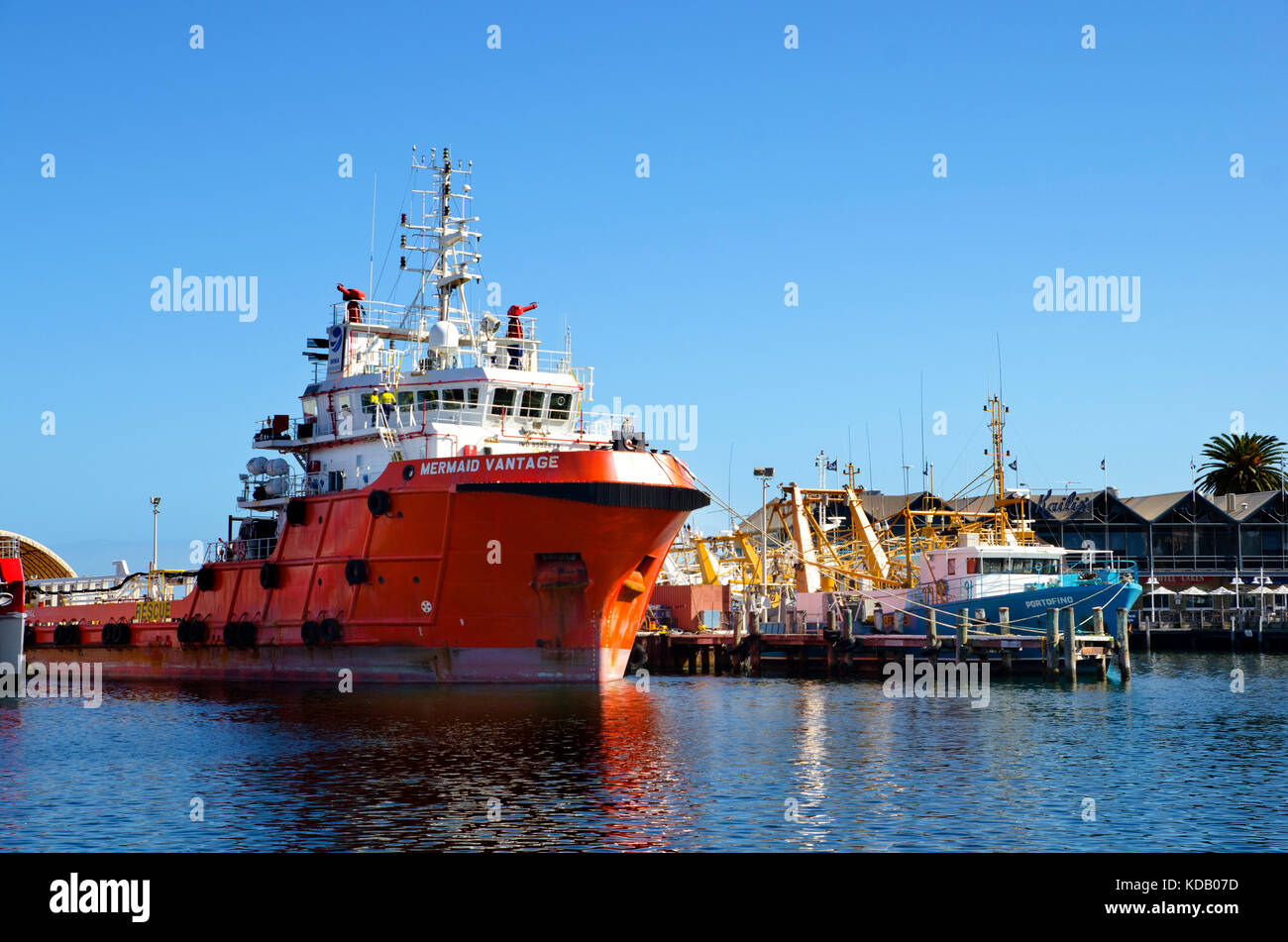 Orange hulled off shore tender ship moored at Fishing Boat Harbour Fremantle Stock Photo