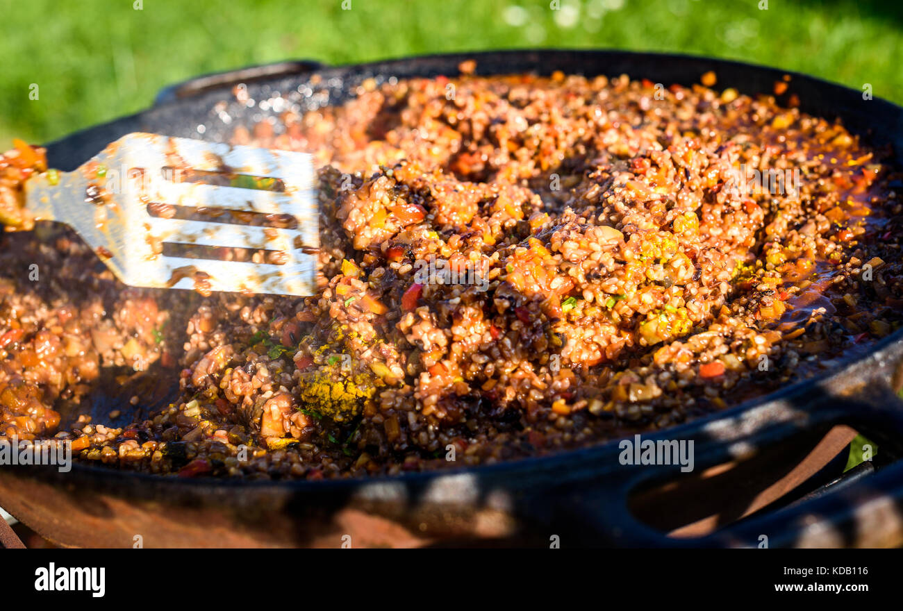 Cooking and making traditional Spanish Paella in iron cast pan