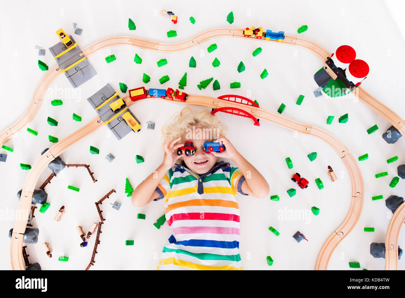 Kids play with toy train railway. Child playing with wooden trains